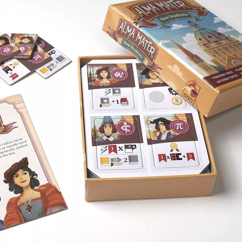 A picture of the open box and components of the promo New Students for the board game Alma Mater. Inside the box are a punchboard of cardboard rectangles and the promo rulebook is partially visible.