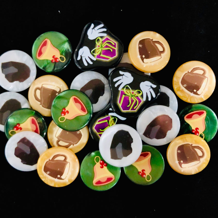 A pile of plastic tokens for use with the board game Dice Throne: Santa vs. Krampus, sitting on a black background. The tokens have illustrations of a mug, lump of coal, bell, and hands with a gift.