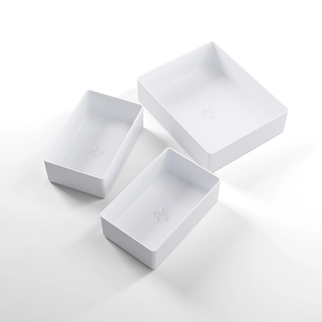 A photo of three, white, plastic containers, two small and one large, on a white background.