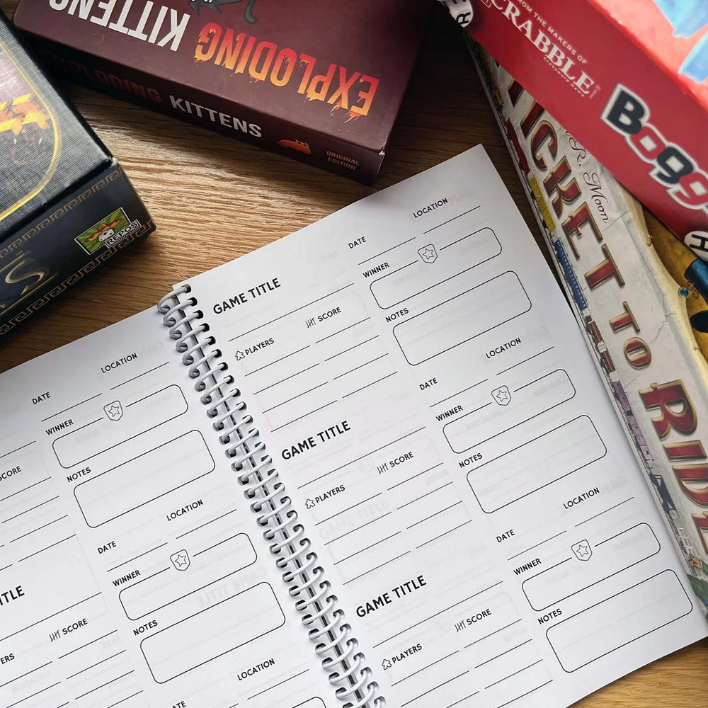 A spiral bound notebook open to show both pages. The pages have sections to record aspects of playing board games.