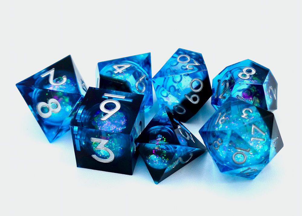 A pile of seven dice on a white background, each one a different shape, made from transparent plastic that is black and deep blue, and contains a circular cavity in the middle filled with glitter and liquid.