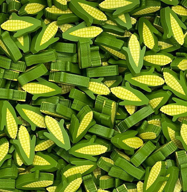 A photo of a pile of corn tokens, featuring both the corn kernels and some green husks.
