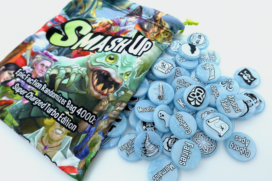 A photo of upgrades for the card game Smash Up, featuring an illustrated fabric, drawstring bag, and a pile of light blue plastic tokens with either words or a simple black and white illustration printed on them.