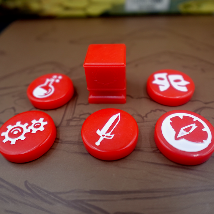 A close up photo of the red GeekUp tokens for use with the board game Tapestry. Five of the bits are circular disks, each with an engraved symbol in the center. The remaining token is a square, plastic column with a laurel wreath printed on each side.