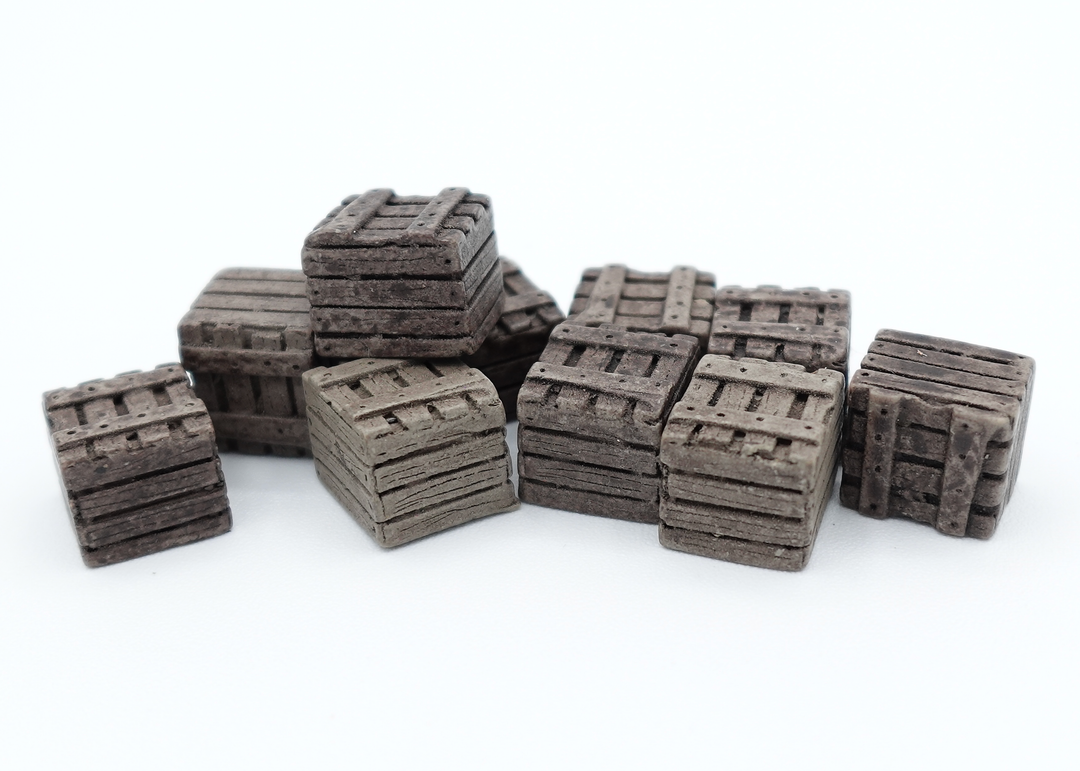 A close up photo of a group of tokens shaped and painted to look like wooden crates, sitting on a white background.