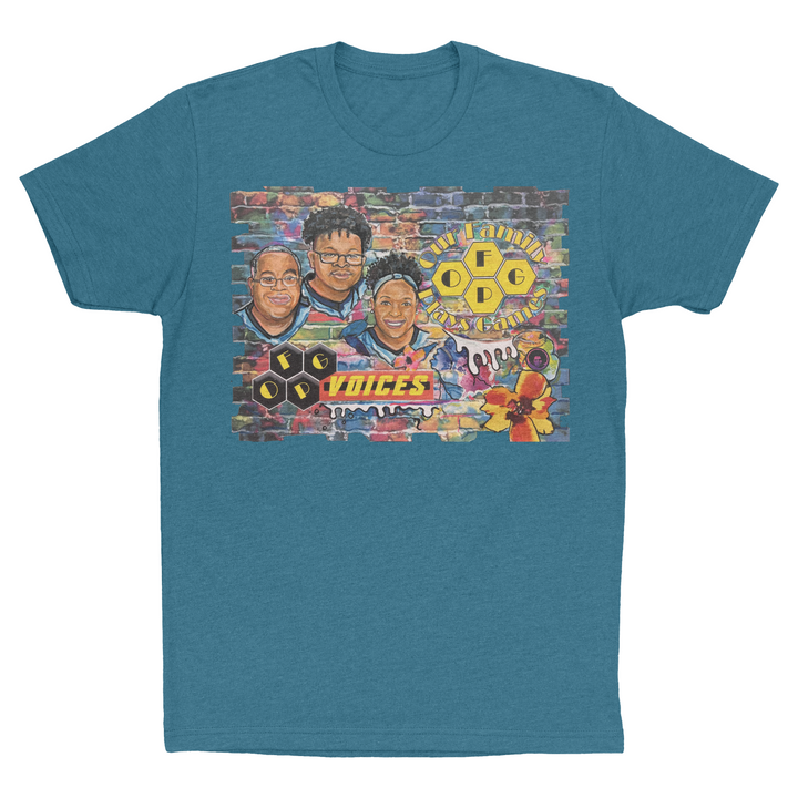 A photo of a teal t-shirt with artwork from Our Family Plays Games. This artwork features three black faces, two man and one woman, against a colorful brick background, and has the words" Our Family Plays Games" and "OFPG Voices".
