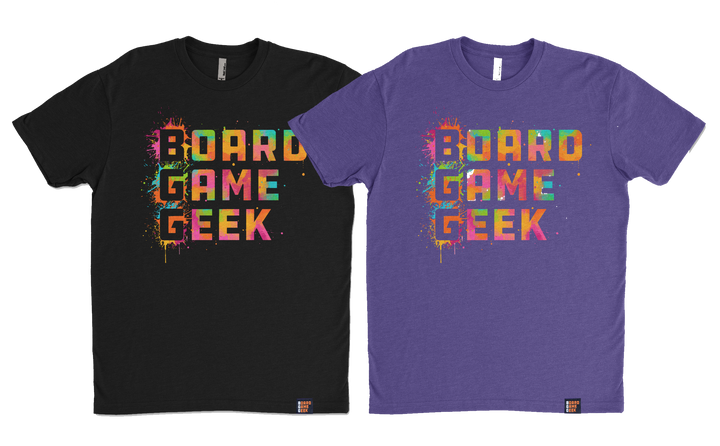 A photo of two shirts, one in black and one purple, both the words "BoardGameGeek" written in colorful, splattered paint.