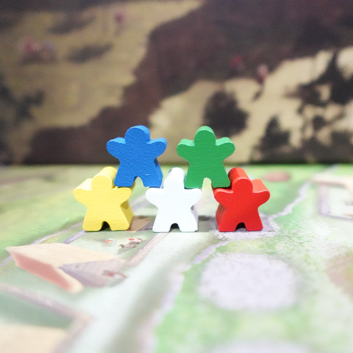 A closeup photo of a mini-expansion for the board game Tawantinsuyu, featuring five people-shaped wooden tokens on a game board, each one a different color. 