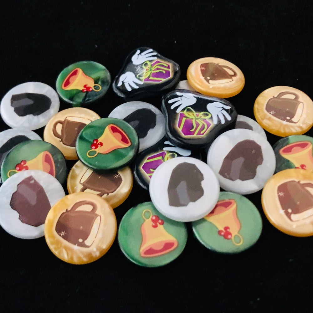 A pile of plastic tokens for use with the board game Dice Throne: Santa vs. Krampus, sitting on a black background. The tokens have illustrations of a mug, lump of coal, bell, and hands with a gift.