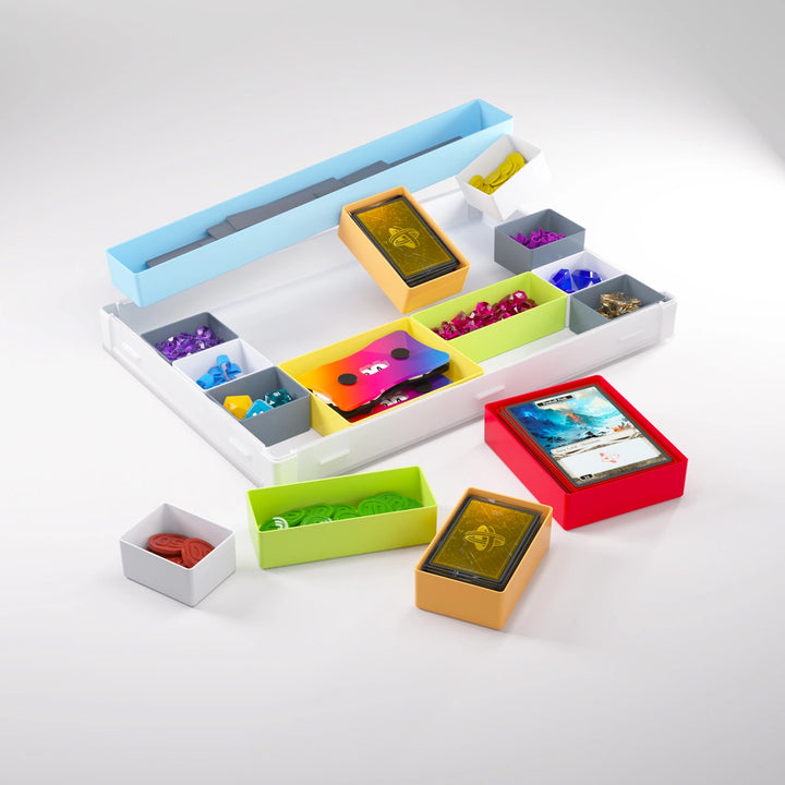 A photo of a white container on a white background. The lid is removed from the container and clipped to the bottom. Smaller multicolored containers, each holding a variety of board game accessories and components, are either inside the container, sitting nearby, or floating above.
