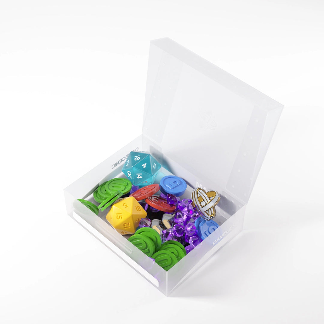 A photo of a clear, plastic box with the lid open on a white background. The lid is open and the box is filled with board game pieces, like dice, plastic gems, and plastic coins.