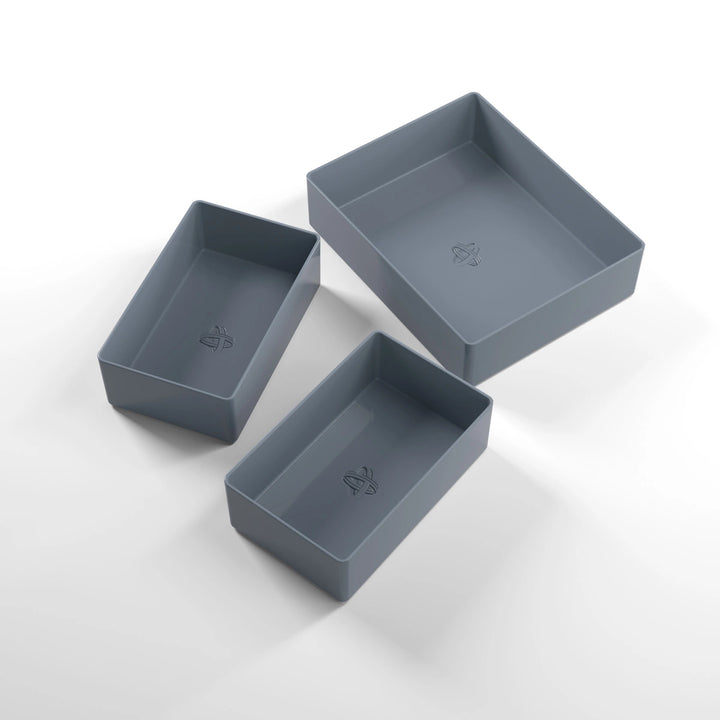 A photo of three, dark gray, plastic containers, two small and one large, on a white background.