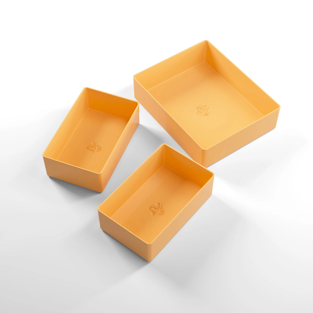 A photo of three, orange, plastic containers, two small and one large, on a white background.