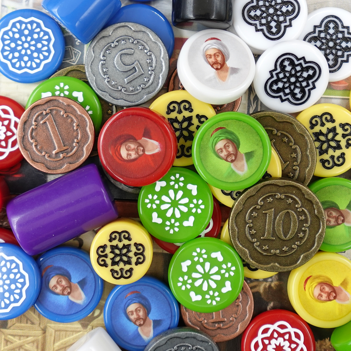 An overhead photo of a jumble of GeekUp bits for use with the board game Istanbul. Some tokens have an illustration of a man in a turban printed on them. Some tokens are engraved and filled with white paint and some are metal coins.