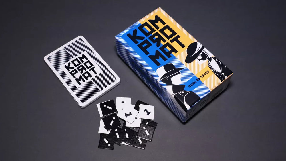 A photo of the box, card backs, and cardboard tokens from the board game Kompromat. The box is half blue, and half orange, with a stylized illustration of a man and woman on each side in black and white. The card back display the name of the game and a striped black and white pattern. The cardboard tokens are black with an "i" printed on one side, and white with a "1" printed on the other.