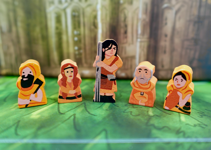 A close up photo of five wooden people tokens made from wood, with faces and clothes painted on one side, and the sides painted orange.