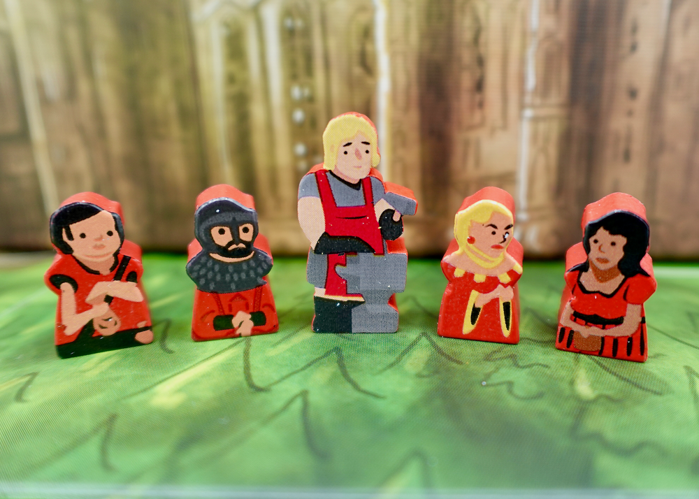 A close up photo of five wooden people tokens made from wood, with faces and clothes painted on one side, and the sides painted red.