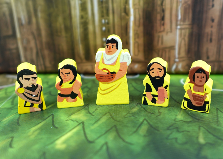 A close up photo of five wooden people tokens made from wood, with faces and clothes painted on one side, and the sides painted yellow.