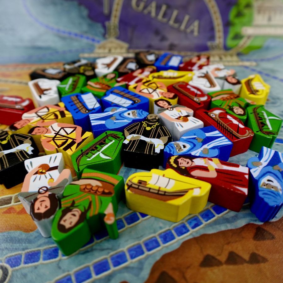 A pile of wooden tokens for use with the board game Concordia, featuring people with ancient Green clothing and boats of the same time period, in a variety of painted colors.