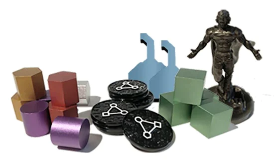 A photo of various, small metal pieces in a variety of shapes: cylinders, disks, cubes, and a figure of a standing man.