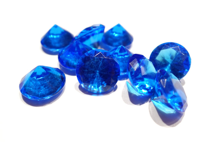 A photo of 10 blue, transparent plastic gems on a white background.