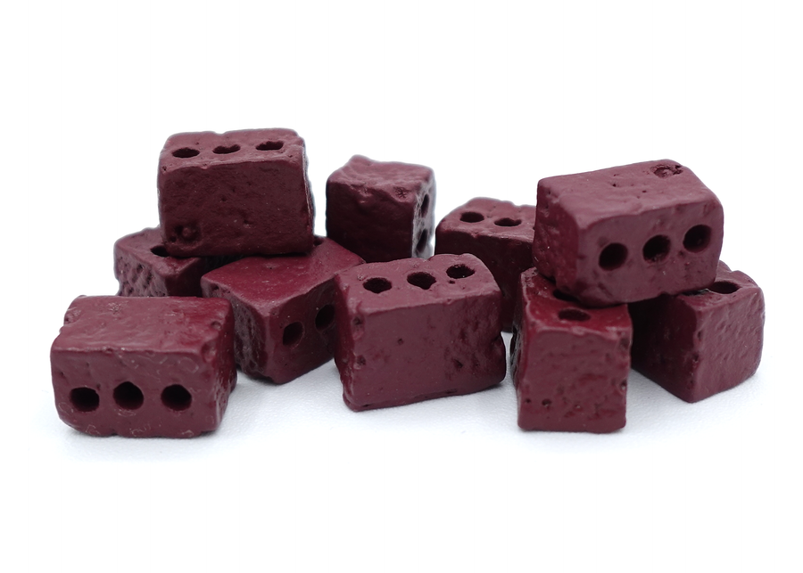 A close up photo of a group of tokens shaped and painted to look like loose bricks, sitting on a white background.
