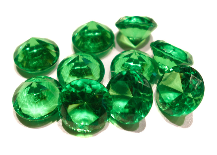 A photo of 10 green, transparent plastic gems on a white background.