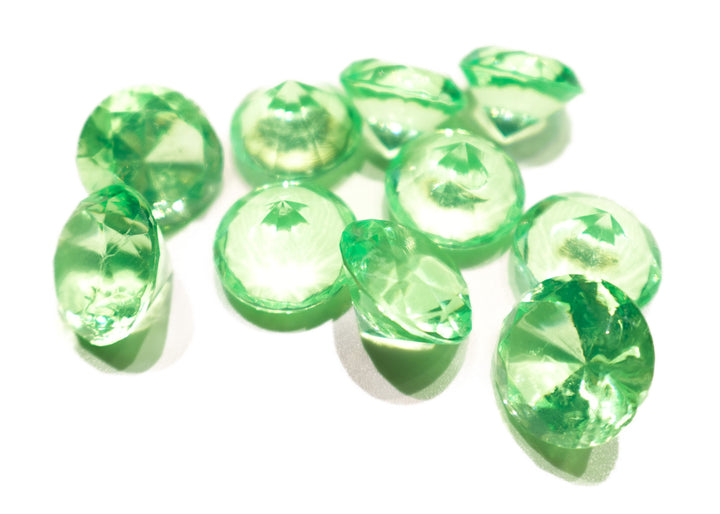 A photo of 10 lime green, transparent plastic gems on a white background.