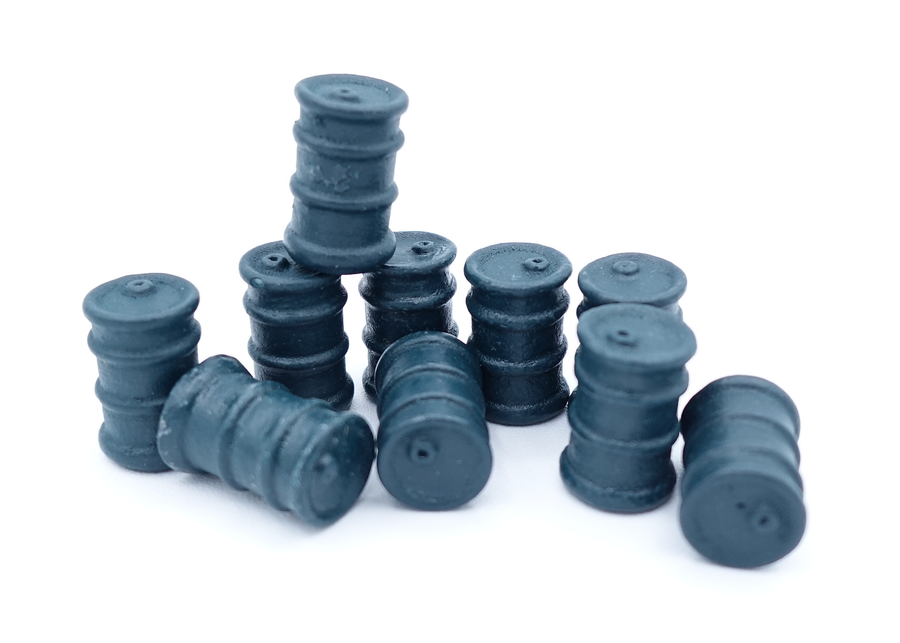 A close up photo of a group of tokens shaped and painted to look like a black oil barrel, sitting on a white background.