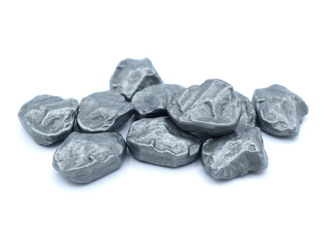 A close up photo of a group of metal tokens shaped to look like raw metal ore, sitting on a white background.