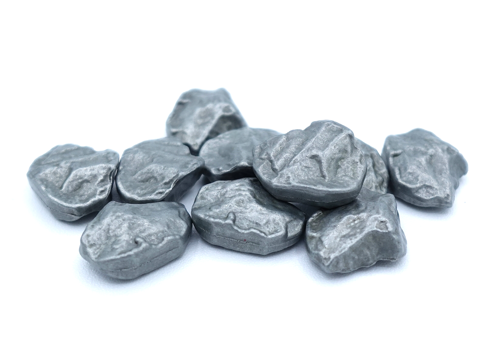 A close up photo of a group of metal tokens shaped to look like raw metal ore, sitting on a white background.