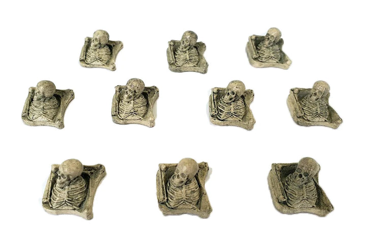 An overhead photo of the fronts of 10, identical 3D molded game pieces that looks like a skull and ribcage resting on top of a pile of bones.