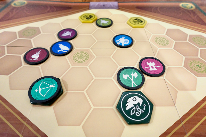 A photo of the game board from War Chest, featuring both the original game pieces and upgraded plastic hexagon tokens, all sitting within a hexagon grid.