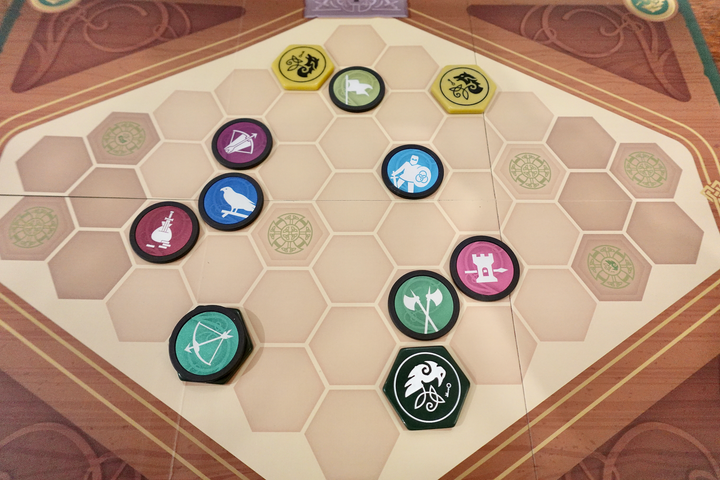 An overhead photo of the game board from War Chest, featuring both the original game pieces and upgraded plastic hexagon tokens, all sitting within a hexagon grid.