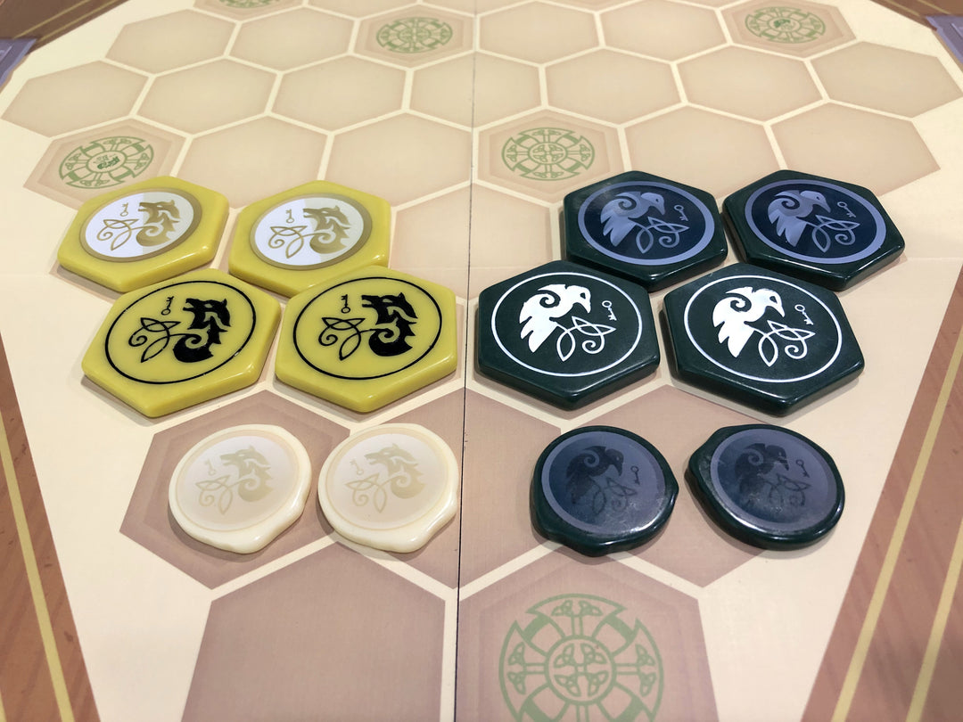 A photo of upgraded plastic tokens for use with the board game War Chest. Half of the tokens are dark gold and half are dark green, some with printed illustrations and some with painted engravings.