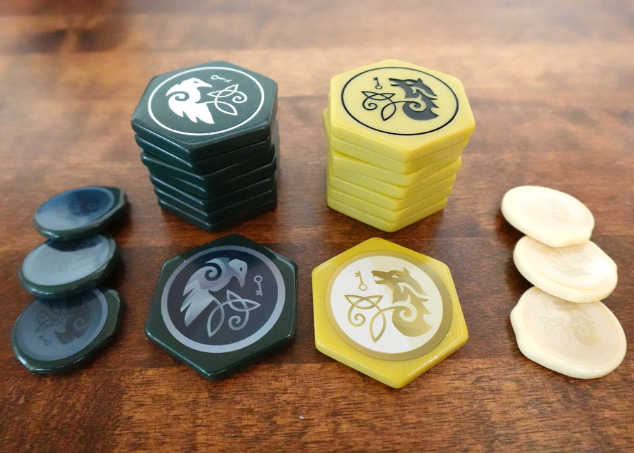 A photo of plastic tokens for use in the board game War Chest in two different colors on a wooden surface.