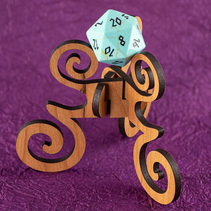 A laser-cut wooden, tripod stand with decorative curves, holding up a 20-sided die, on a purple background