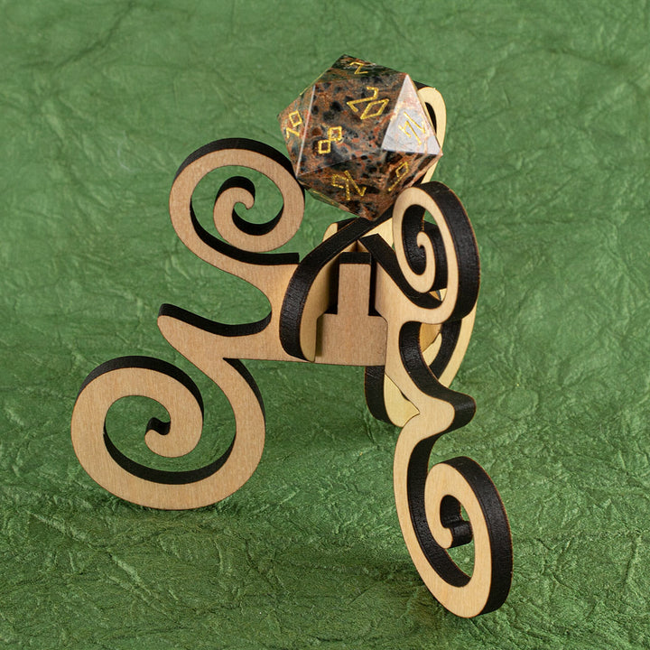 A laser-cut wooden, tripod stand with decorative curves, holding up a 20-sided die, on a purple background