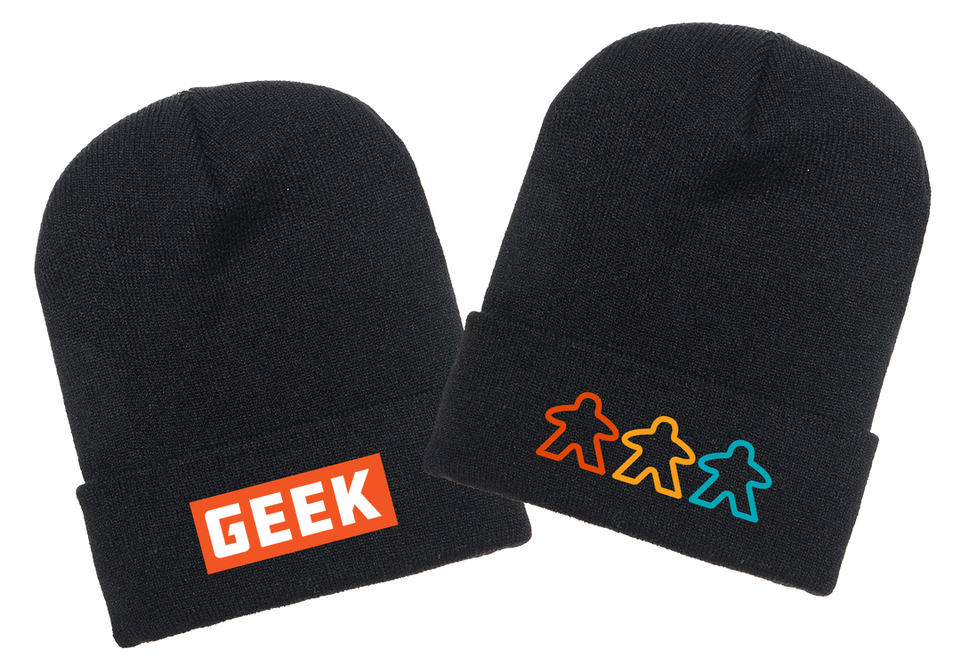 A photo of two black knit ski caps, one with an orange label and the word GEEK written in white, and the other with three outlines of meeples in various colors.