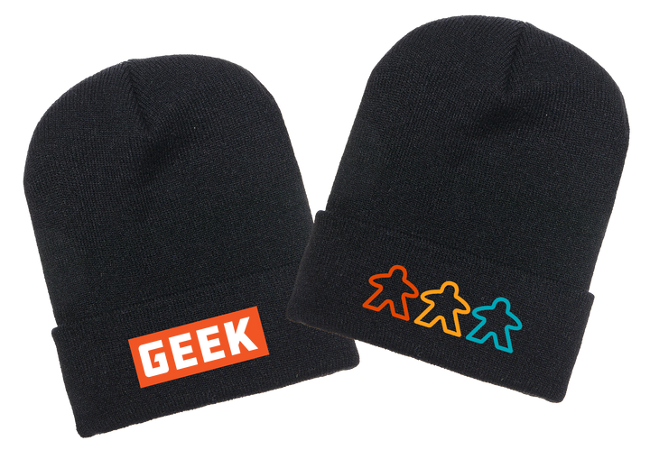 A photo of two black knit ski caps, one with an orange label and the word GEEK written in white, and the other with three outlines of meeples in various colors.