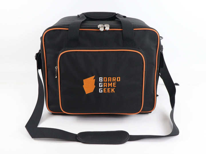 A front view of a black carry bag and backpack with orange trim, and an embroidered logo on the front pocket that reads "BoardGameGeek". The bag has handles on the top and a shoulder strap laid out in front.