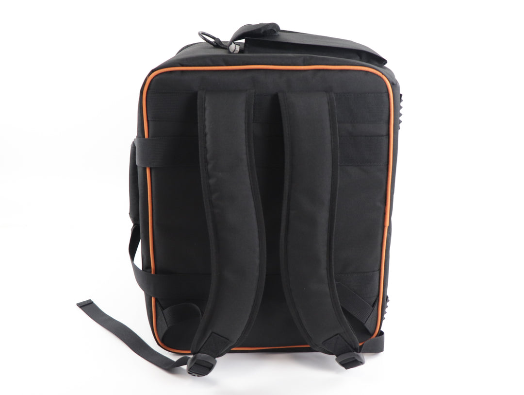 A back view of an upright, black carry bag and backpack with orange trim, and an embroidered logo on the front pocket that reads "BoardGameGeek". The bag has handles on the side and backpack straps running from top to bottom.