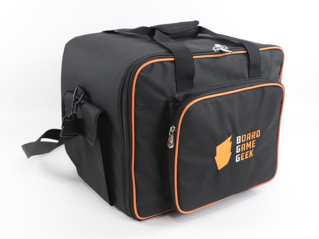 An angled front view of a black carry bag and backpack with orange trim, and an embroidered logo on the front pocket that reads "BoardGameGeek". The bag has handles on the top and a shoulder strap draped in the back.