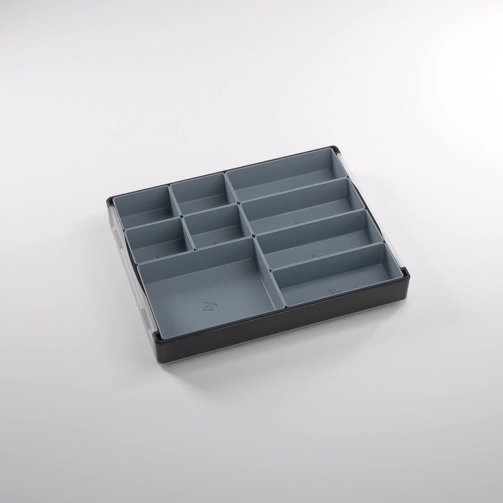 A photo of a empty, black, plastic container on a white background. Inside of this container are smaller sections of various sizes.