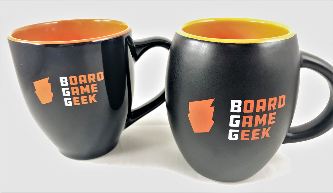 Two black coffee mugs, both with orange on the inside, and are labeled with "BoardGameGeek" on the outside. The mug on the left is bistro shaped and glossy, while the mug on the right is barrel shaped and matte.