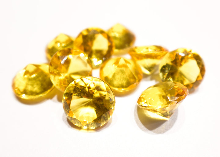A photo of 10 gold, transparent plastic gems on a white background.