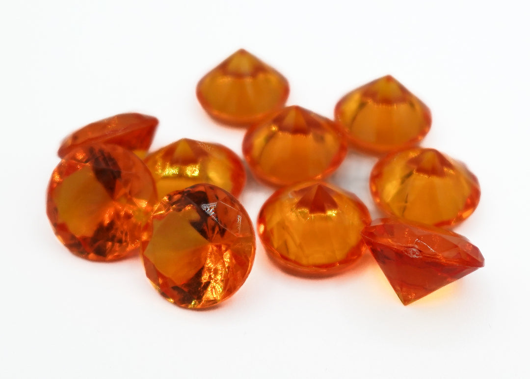 A photo of 10 orange, transparent plastic gems on a white background.