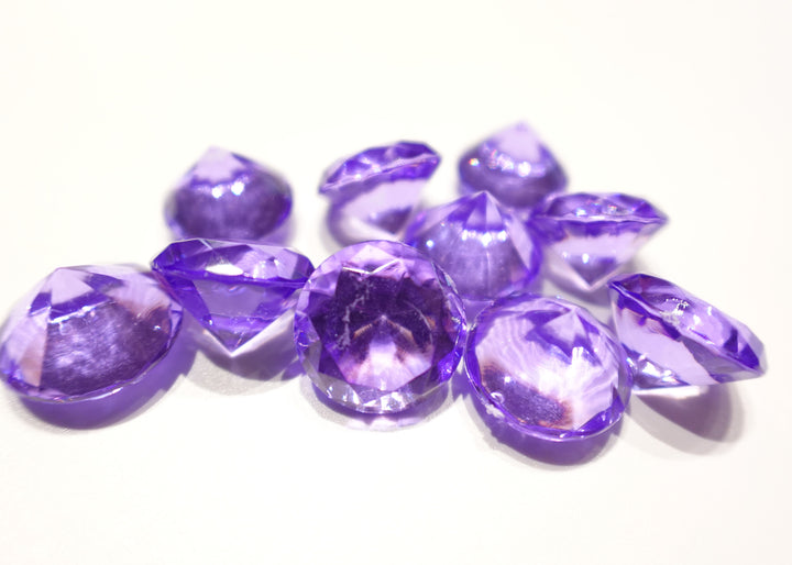 A photo of 10 purple, transparent plastic gems on a white background.